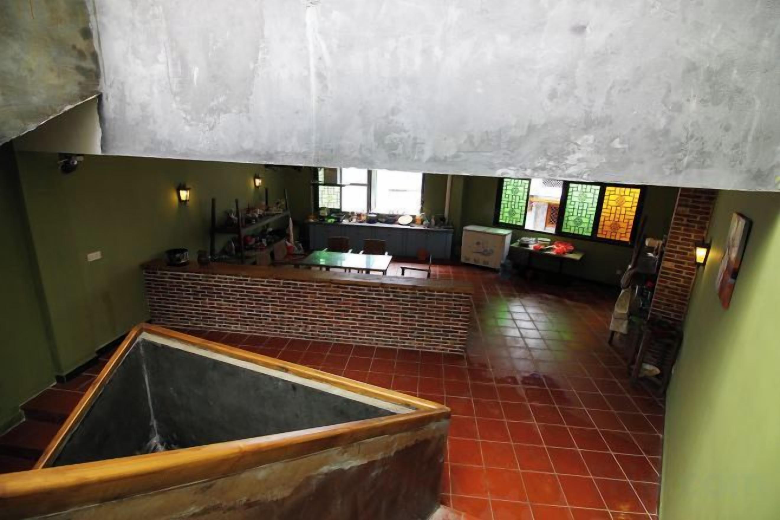 Une pièce spacieuse avec un grand espace ouvert, une structure en briques et une vue sur la cuisine.