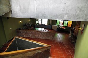 A spacious room with a large open area, a brick structure, and a view of a kitchen area.