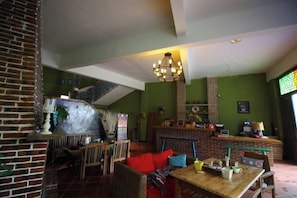 A cozy interior with a brick fireplace, wooden furniture, and a staircase. - Reshui Impression Inn (Rucheng)