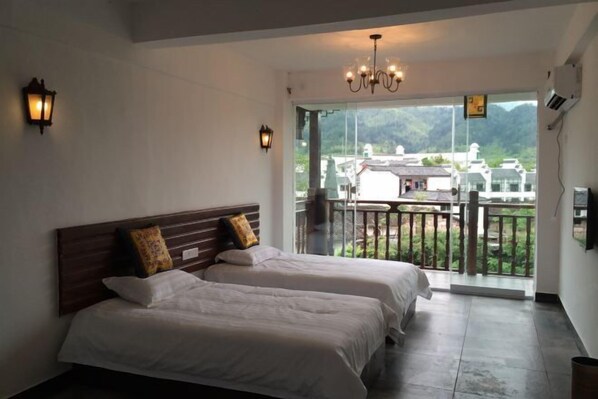 A hotel room with two beds, a balcony with a view of the mountains, and a chandelier. - Reshui Impression Inn (Rucheng)
