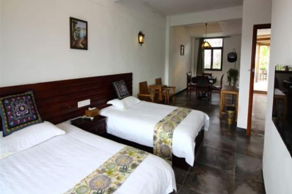 A hotel room with two beds, a desk, and a chair.