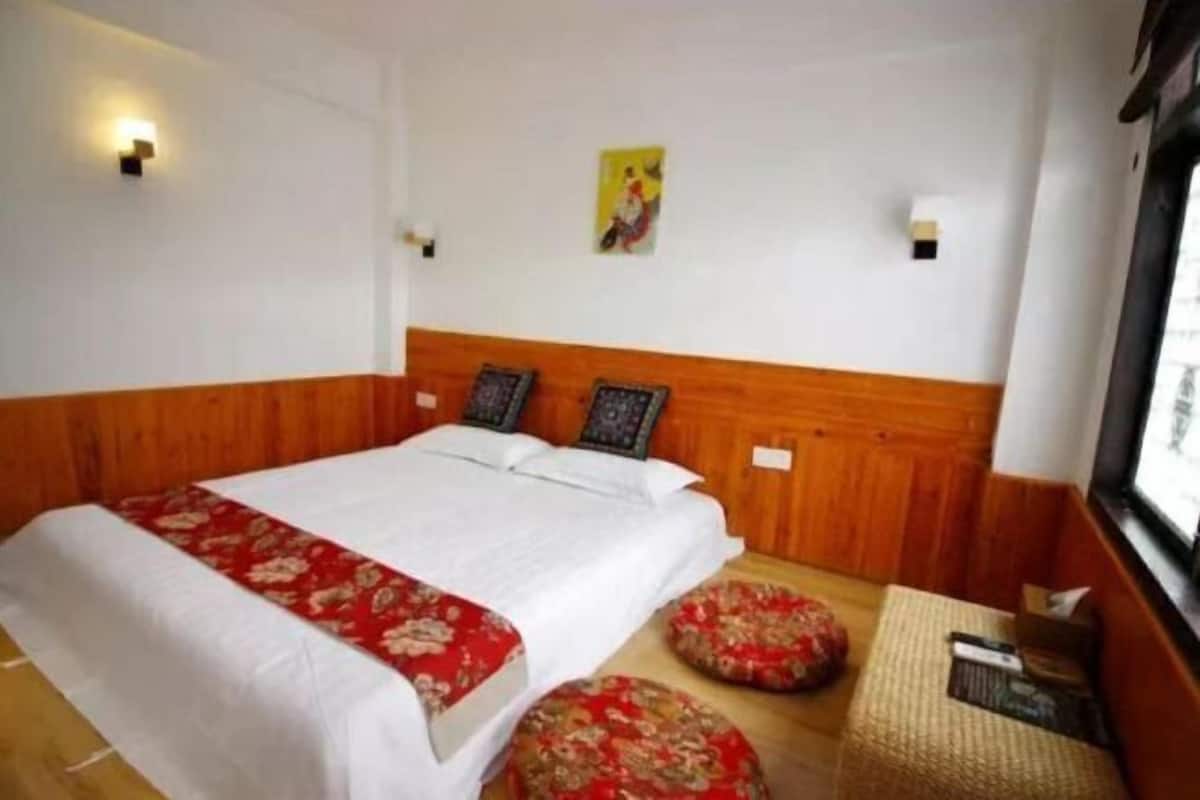 A hotel room with a large bed, two wall-mounted lights, a wooden headboard, and a window with a view.