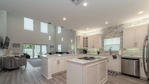 Una cocina moderna con armarios blancos, una isla central y un refrigerador de acero inoxidable.