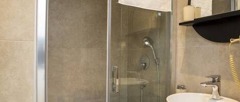 A modern bathroom with a glass-enclosed shower, a white sink, and a mirror above it.