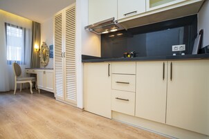 Una cocina moderna con armarios de colores claros, encimera negra y estufa integrada.