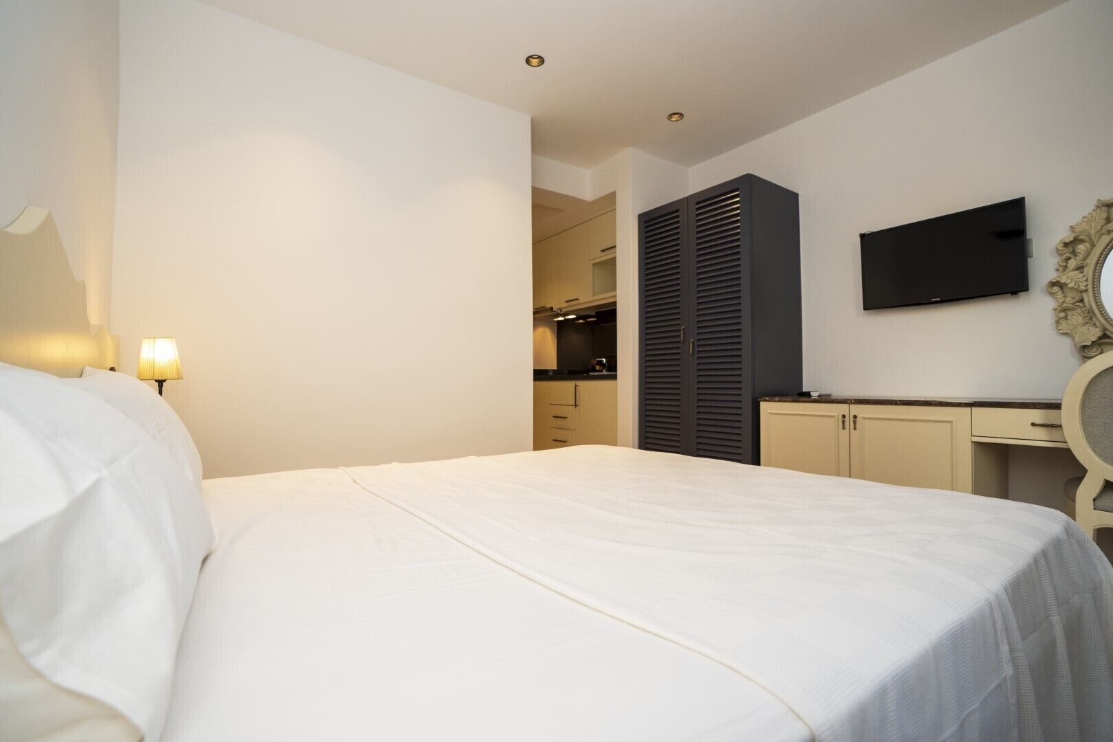A bedroom with a bed, a desk, a television, and a wardrobe.