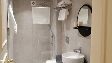 A modern bathroom with a toilet, sink, shower, and a washing machine.