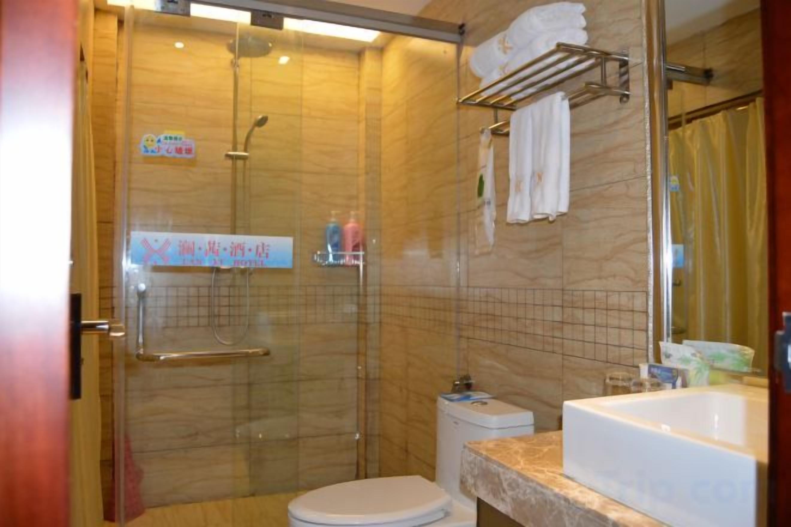 Une salle de bain avec une douche à parois de verre, des toilettes, un lavabo et un miroir.