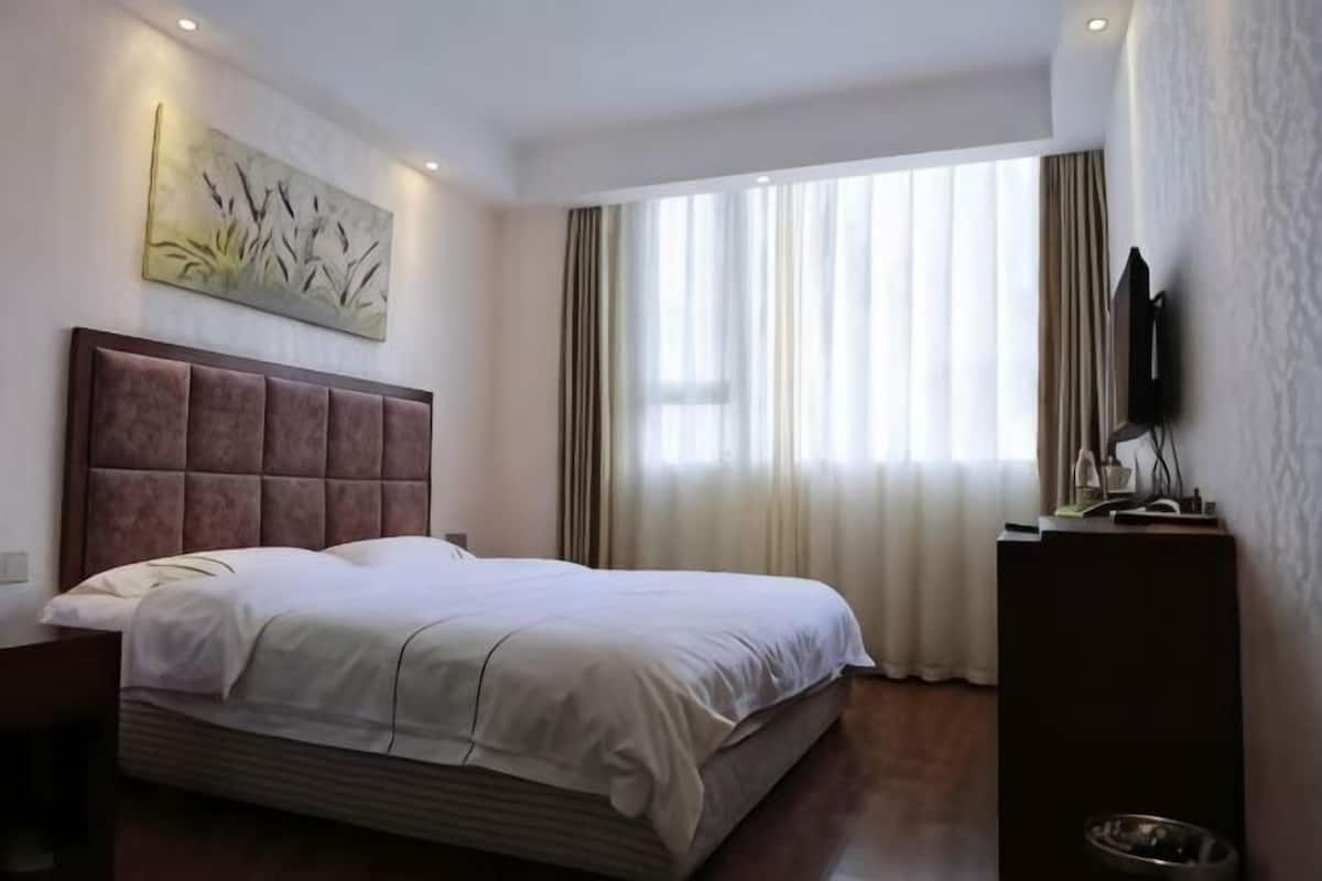A hotel room with a large bed, a flat-screen TV, and a painting on the wall.