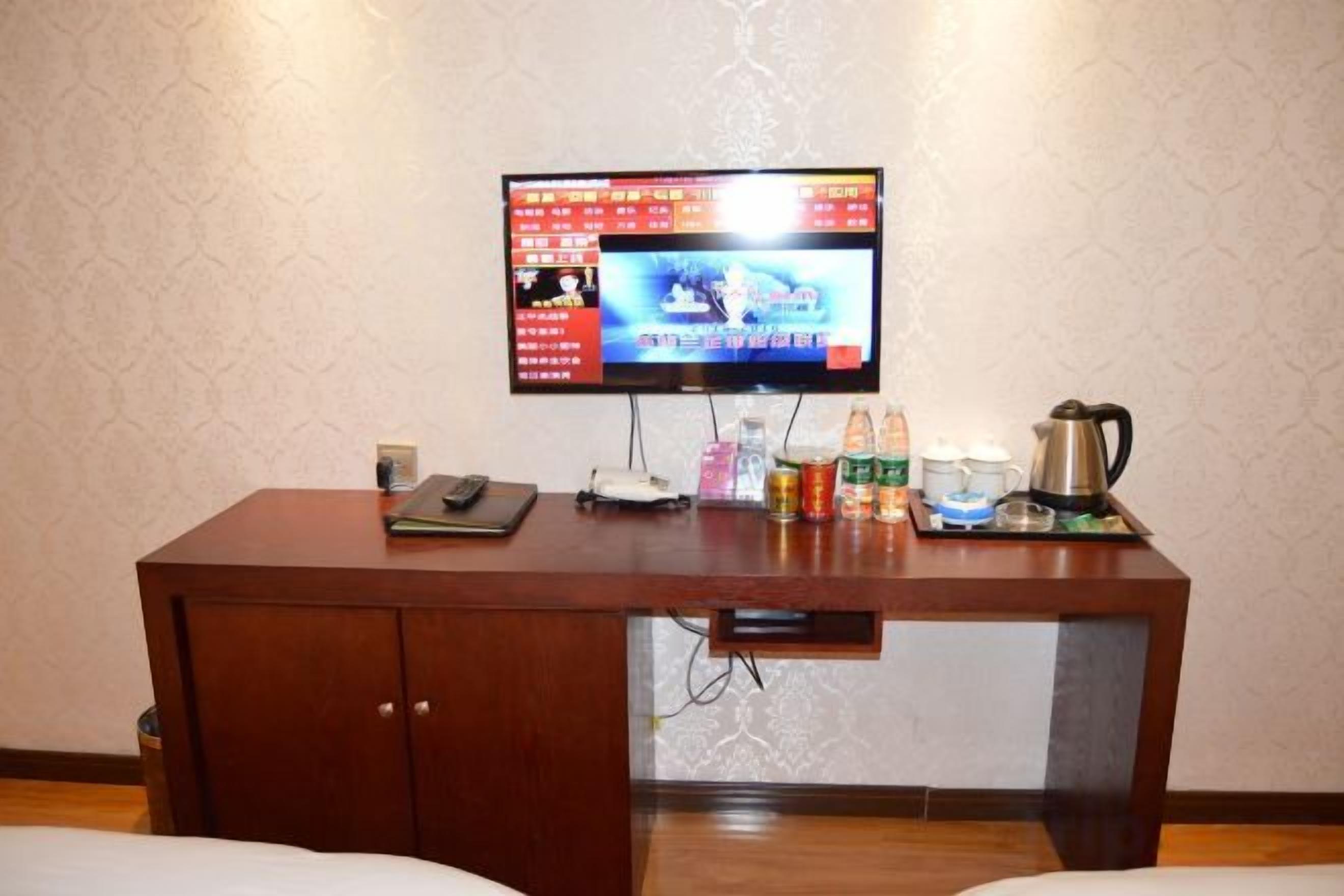 Una habitación de hotel con un escritorio de madera, un televisor y una cafetera.