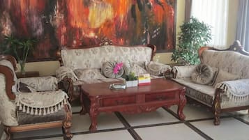 A room with a sofa set, a coffee table, and a large abstract painting on the wall.