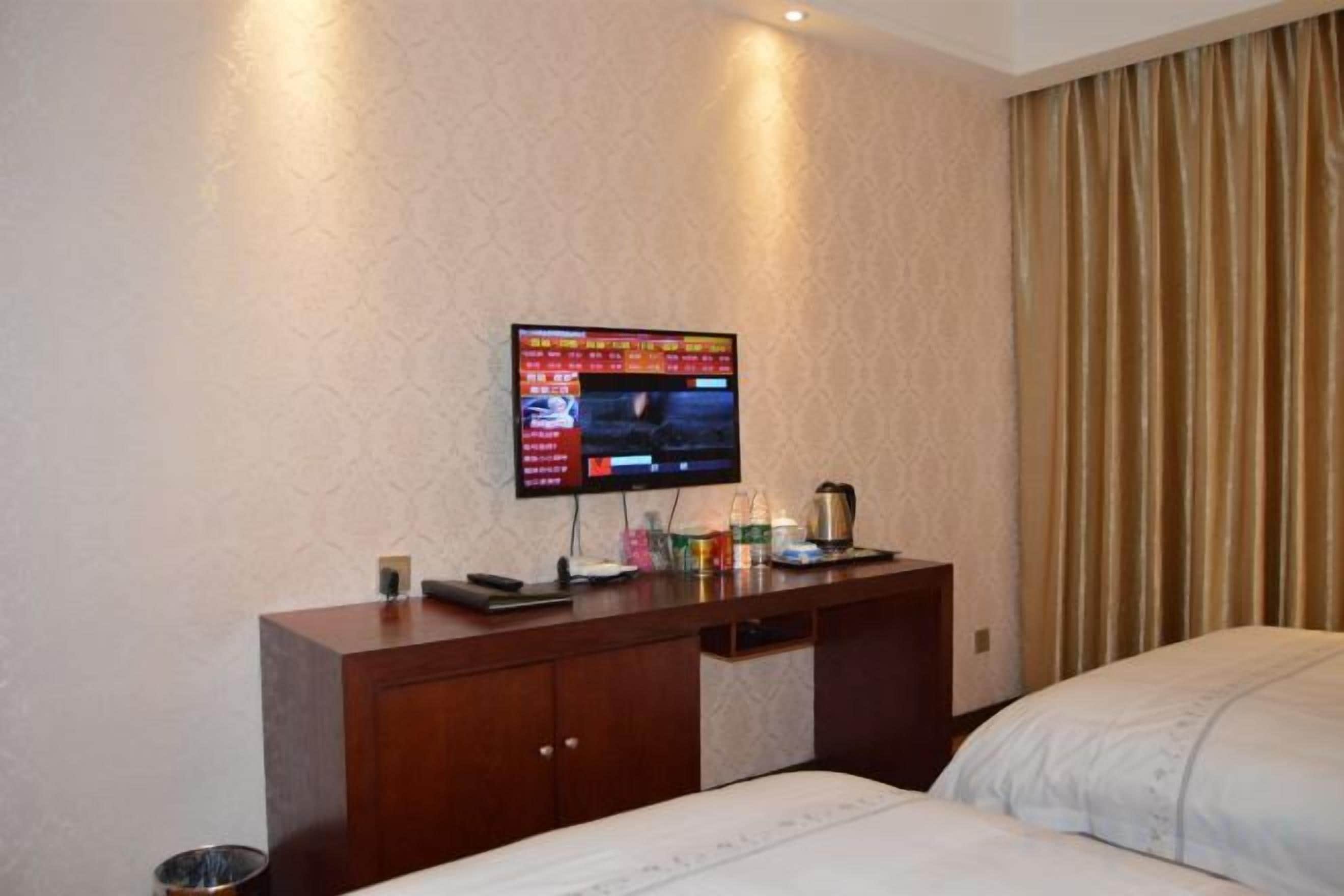 Une chambre d’hôtel avec un lit, un bureau doté d’un téléviseur à écran plat et un rideau.
