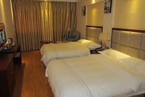 Habitación de hotel con dos camas, un escritorio, una silla y un ventanal con cortinas.