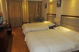 Habitación de hotel con dos camas, un escritorio, una silla y un ventanal con cortinas.