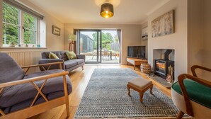 Amplia sala de estar con chimenea, televisión y un ventanal grande con vistas a un jardín.