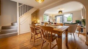 Un comedor amplio con una mesa y sillas de madera, una escalera y vistas al exterior.