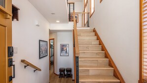 A staircase with wooden steps and a handrail, leading to a landing with a small stool and a framed picture.