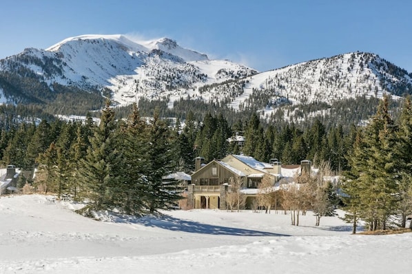Paisaje montañoso cubierto de nieve con una casa en primer plano.