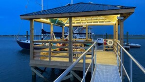 Un muelle de madera con un área techada, un bote y un flotador.