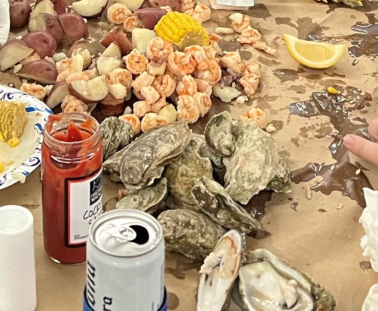 A table with seafood including shrimp, oysters, and corn on the cob.