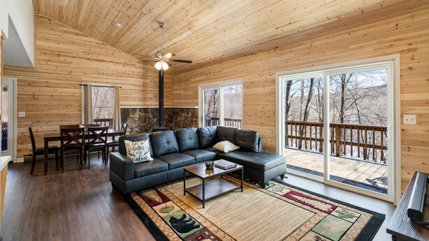 A spacious living room with a black leather sofa, a coffee table, and a wooden ceiling. - ★Cabin: Pet/Family Friendly, Hot Tub, Large Deck★ (Berkeley Springs)