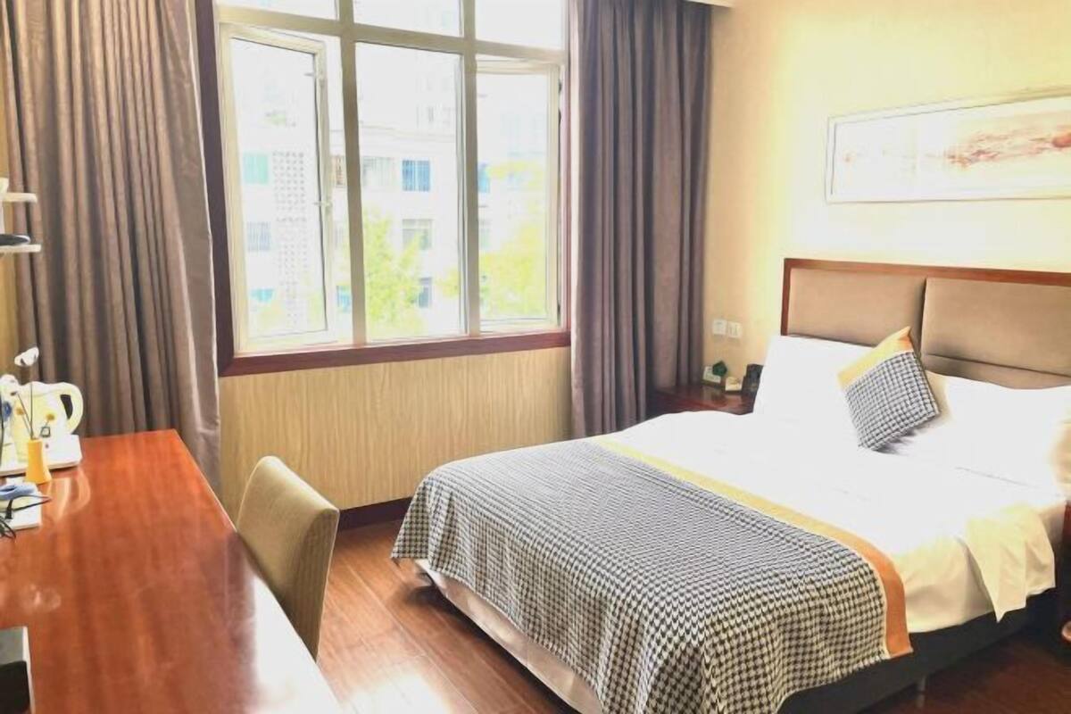 A hotel room with a bed, a desk, and a window.