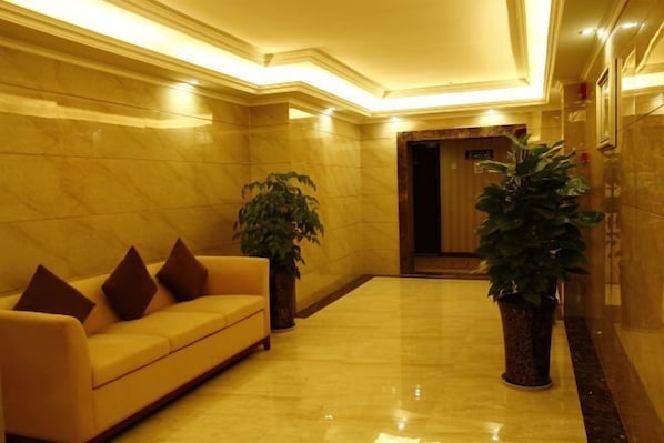 A lobby with a yellow sofa, two potted plants, and a marble floor. - Jinhao Hotel (Chengdu)
