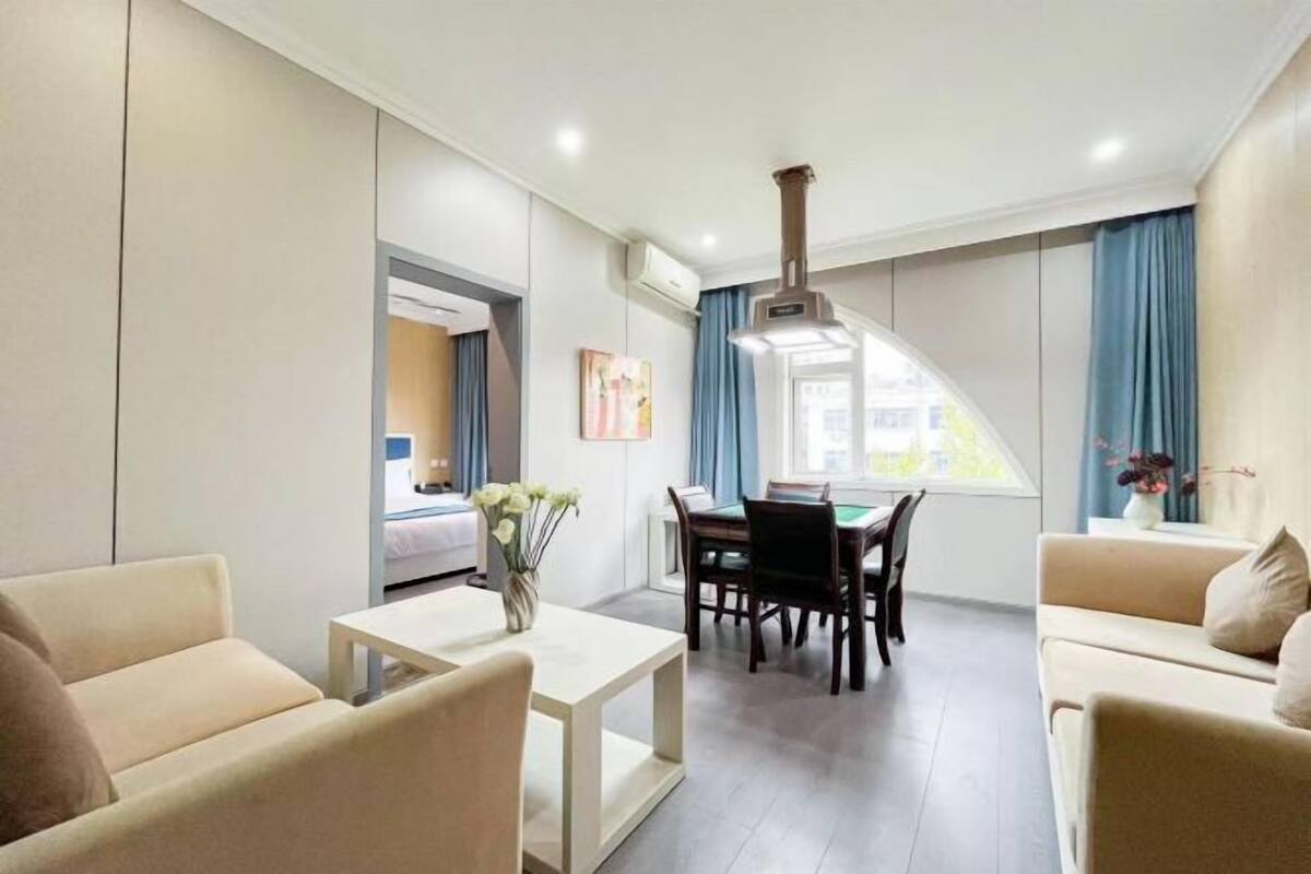 A modern living room with a dining area, a sofa, a coffee table, and a view of the outside.