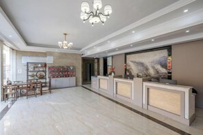 Un hall d’hôtel comprenant un comptoir d’accueil, un espace repas et une grande peinture abstraite accrochée au mur.