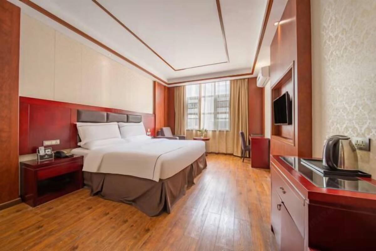 Ein Hotelzimmer mit Bett, Nachttisch, Fernseher und einer Küchenzeile.