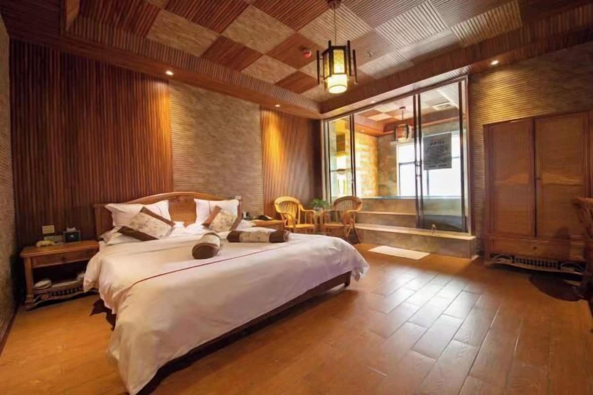 Ein Schlafzimmer mit einem großen Bett, Holzwänden, einem Fenster mit Ausblick und einer Schiebetür.