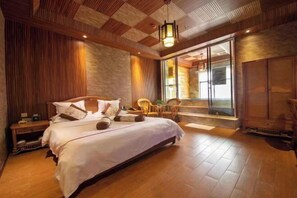 Un dormitorio con una cama grande, paneles de madera, un ventanal con vistas y una puerta corrediza.