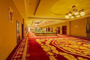 Un pasillo de hotel con alfombra roja, obras de arte enmarcadas en las paredes y un candelabro.