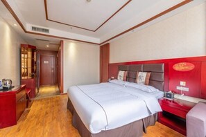 Habitación de hotel con una cama grande, un escritorio con silla y una pared de acento roja.