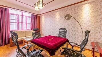 A room with a dining table, four chairs, a sofa, and a large window with curtains.