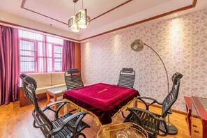 Una habitación con una mesa de comedor, cuatro sillas, un sofá y un ventanal con cortinas.