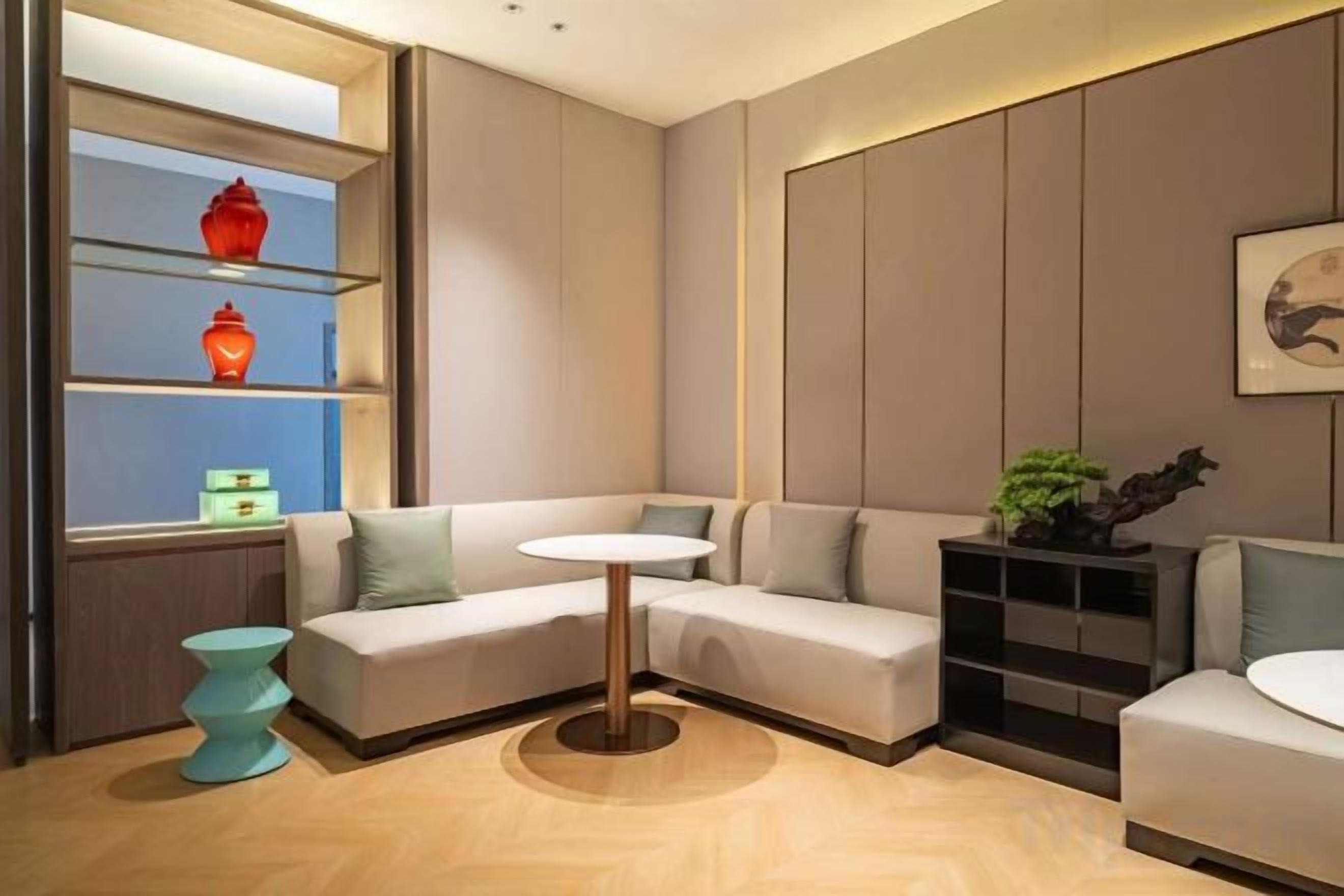A modern living room with a sectional sofa, a small round table, and built-in shelving with decorative items.