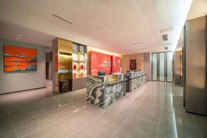 A modern hotel lobby with a reception desk, a large painting, and a glass partition. - Meilan Hot Spring Hotel (Anshun)