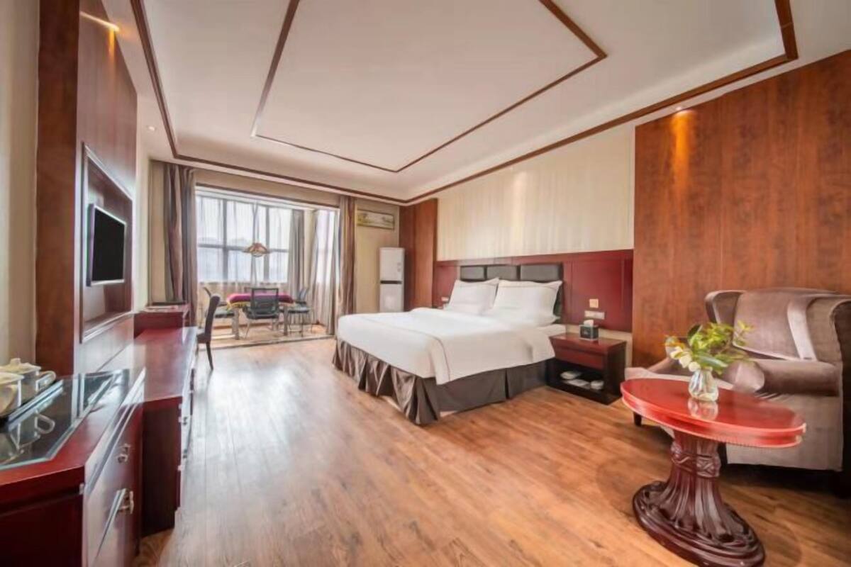 Ein Hotelzimmer mit Bett, Nachttisch, Fernseher und Blick ins Freie.