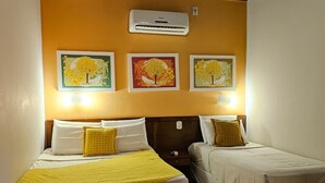 A hotel room with two beds, a wall-mounted air conditioner, and three framed pictures of trees. - Pantanal Hotel (Miranda)