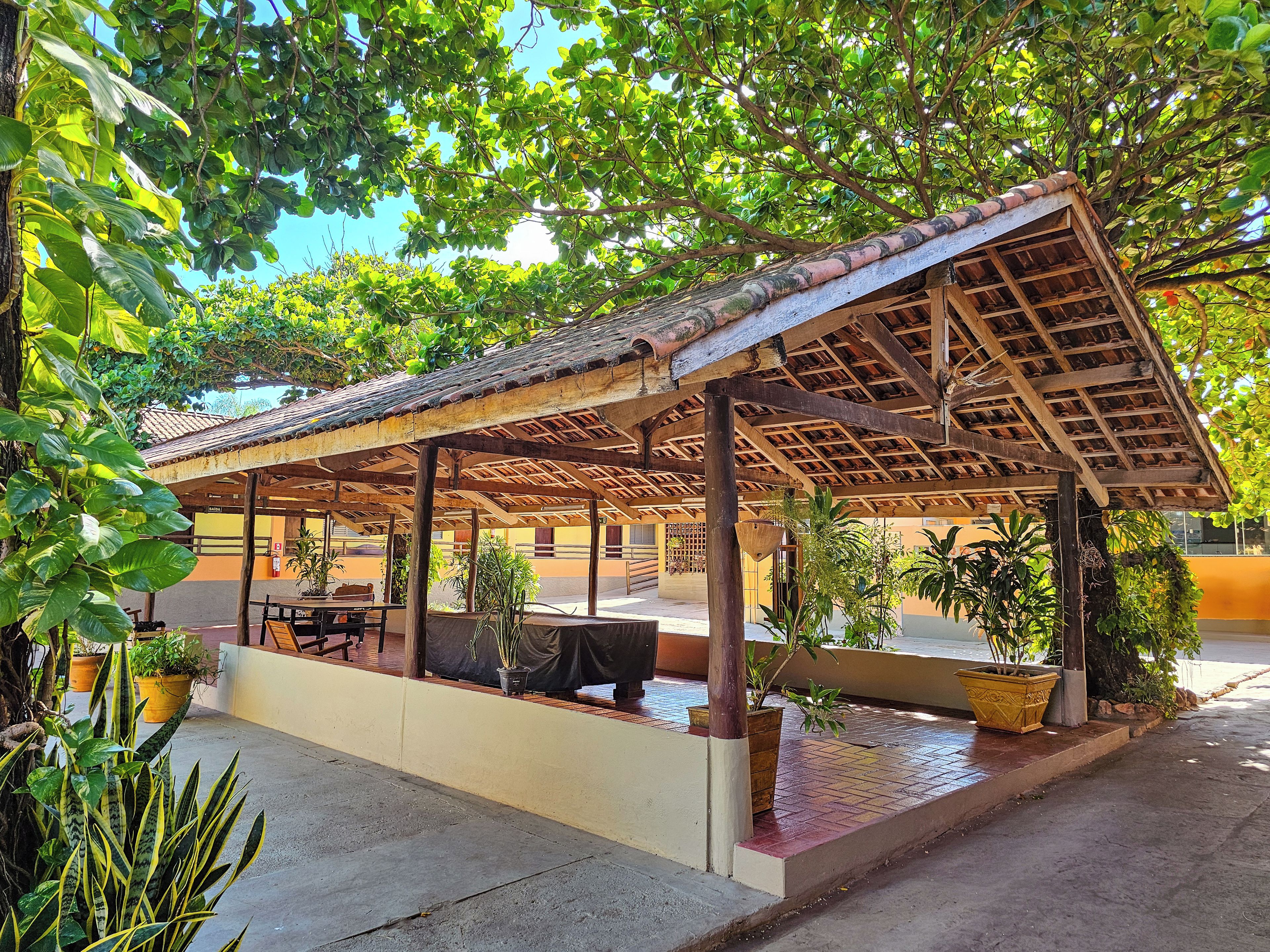 A covered outdoor seating area with potted plants and a table.