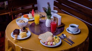 A breakfast setting with plates of food, a glass of orange juice, a glass of red juice, and a cup of coffee on a round table. - Pantanal Hotel (Miranda)