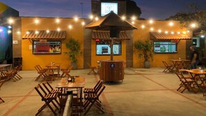 An outdoor dining area with wooden tables and chairs, a trash bin, and a sign for 'MORBIDA'. - Pantanal Hotel (Miranda)