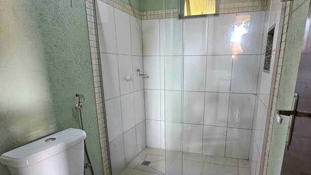 A bathroom with a toilet, a shower stall, and a glass door. - Pantanal Hotel (Miranda)