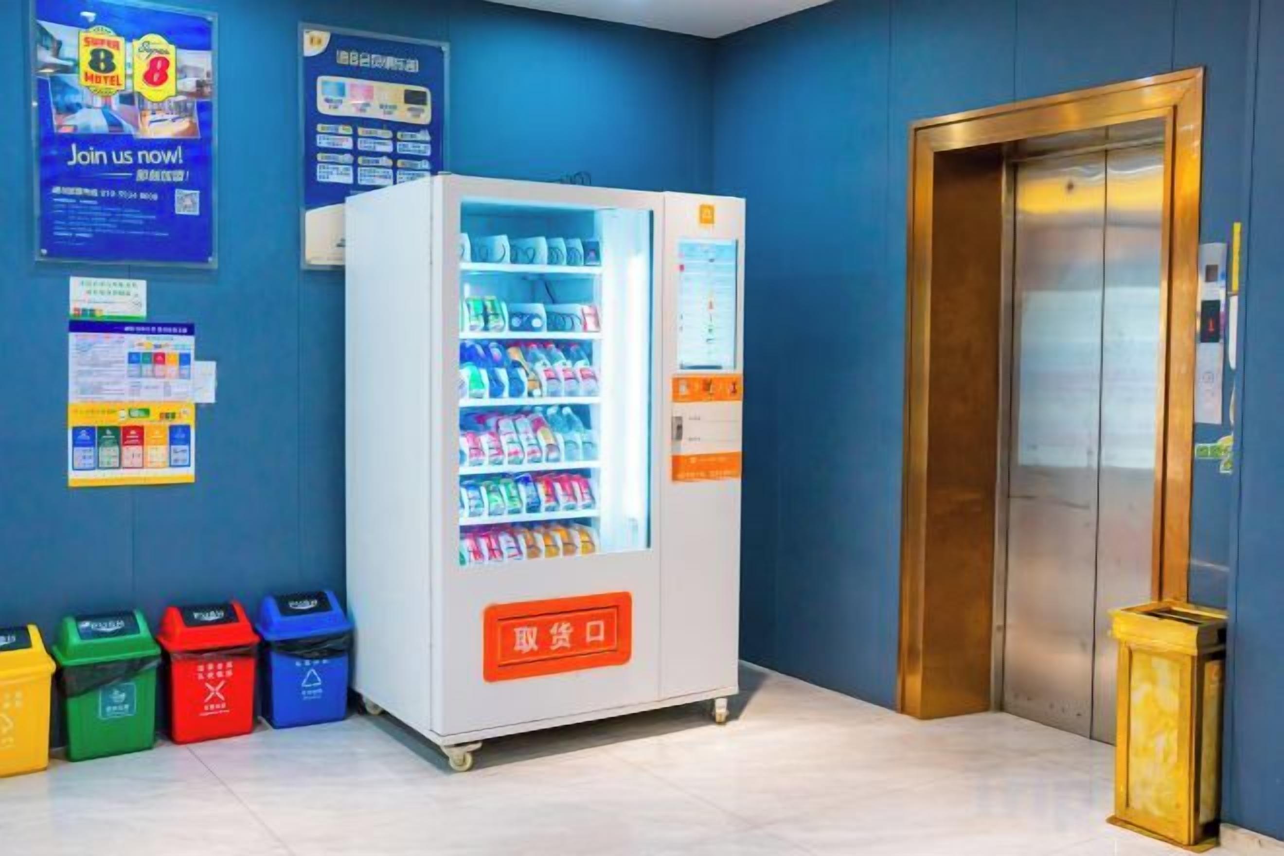 A vending machine with a variety of items, a trash bin, and a door with a handle.