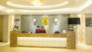 A hotel reception desk with a marble counter, two receptionists, a chandelier, a television, and a wall with a logo and text. - Super 8 Hotel (Xiamen Tong'an Bell Tower) (Xiamen)