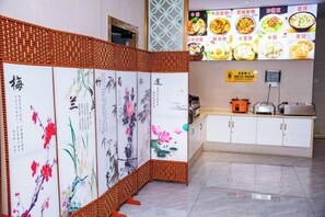 Quarto com um ecrã tradicional chinês, área de cozinha com fogão e torradeira, e uma parede exibindo alimentos.