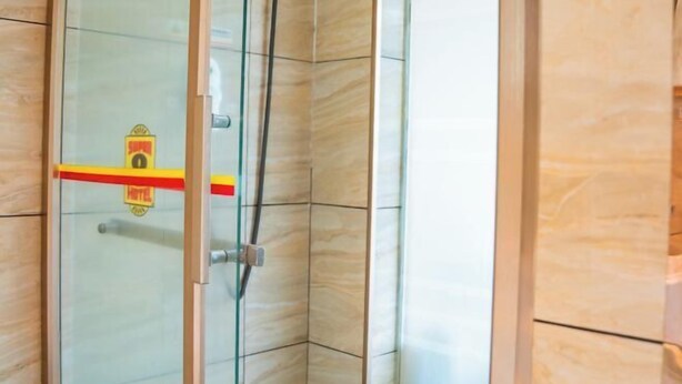 A corner of a room with a glass door, a shower area with a tiled wall, and a wooden floor. - Super 8 Hotel (Xiamen Tong'an Bell Tower) (Xiamen)