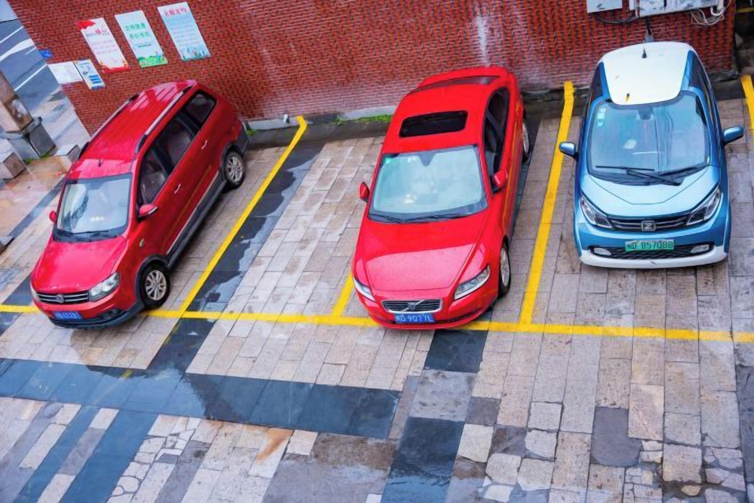 A parking lot with three cars parked in designated spaces.