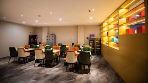 A conference room with multiple tables and chairs, a bookshelf with colorful boxes, and a cabinet in the background. - Super 8 Hotel (Xiamen Tong'an Bell Tower) (Xiamen)